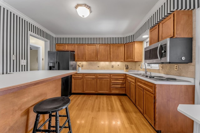 kitchen with backsplash, a kitchen breakfast bar, ornamental molding, light hardwood / wood-style floors, and black fridge