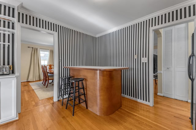 bar with ornamental molding and light hardwood / wood-style floors