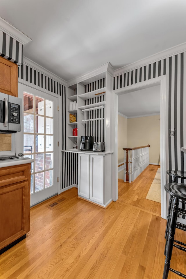 kitchen featuring ornamental molding and light hardwood / wood-style floors