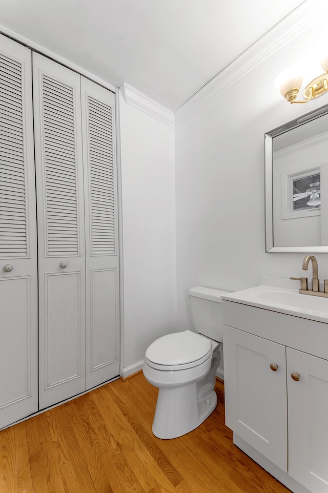 bathroom featuring vanity, hardwood / wood-style floors, crown molding, and toilet