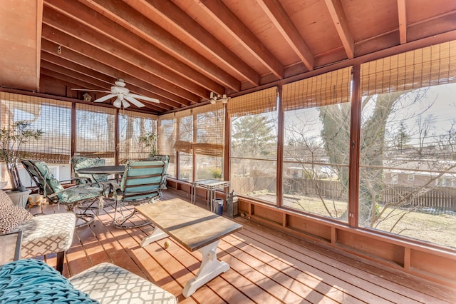 unfurnished sunroom with beamed ceiling, ceiling fan, and plenty of natural light