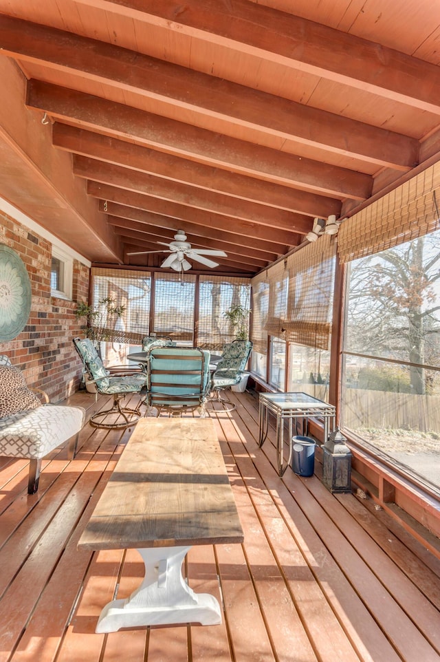 unfurnished sunroom featuring beamed ceiling and ceiling fan