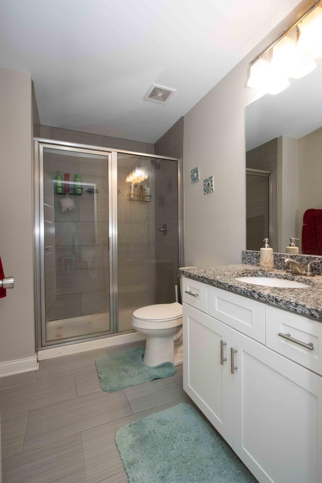 bathroom with vanity, tile patterned flooring, a shower with shower door, and toilet