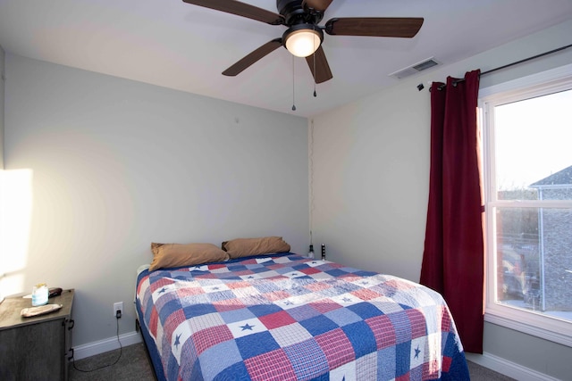 bedroom with multiple windows, dark carpet, and ceiling fan