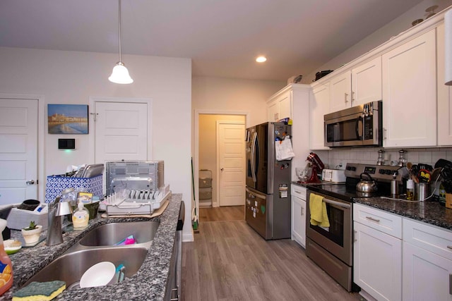 kitchen featuring white cabinetry, sink, backsplash, hanging light fixtures, and stainless steel appliances