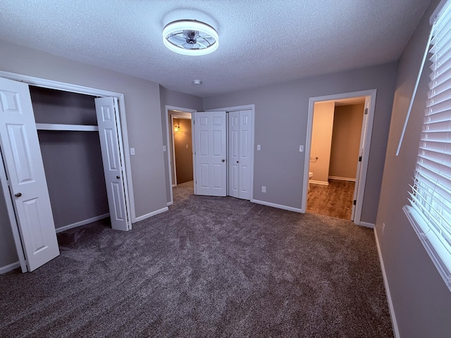 106 Liberty Ave, Berea, KY 40403 - unfurnished bedroom with baseboards, two closets, dark colored carpet, and a textured ceiling