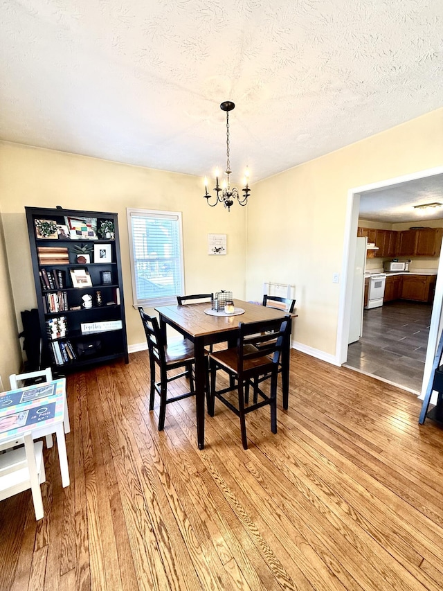 428 Columbia Ave, Monticello, KY 42633 - dining space with a textured ceiling, wood finished floors, a notable chandelier, and baseboards