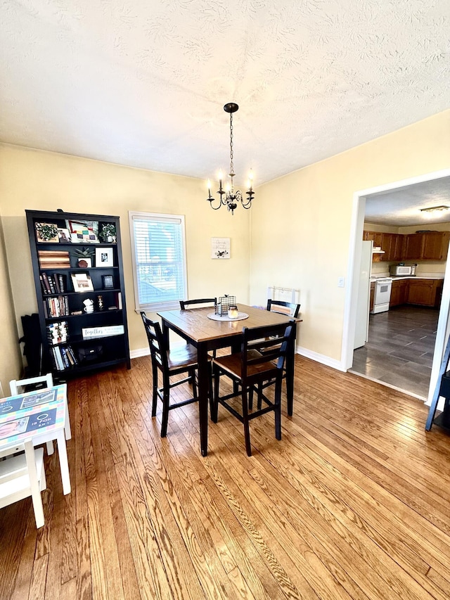 dining area featuring an inviting chandelier, hardwood / wood-style flooring, and a textured ceiling