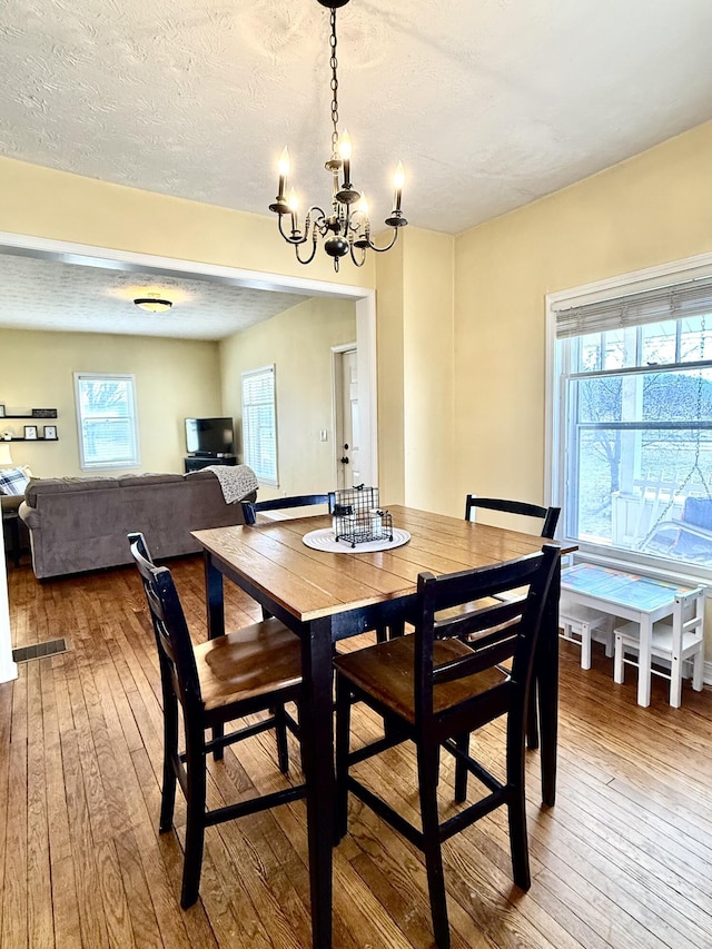 dining area featuring hardwood / wood-style flooring, a chandelier, and a textured ceiling