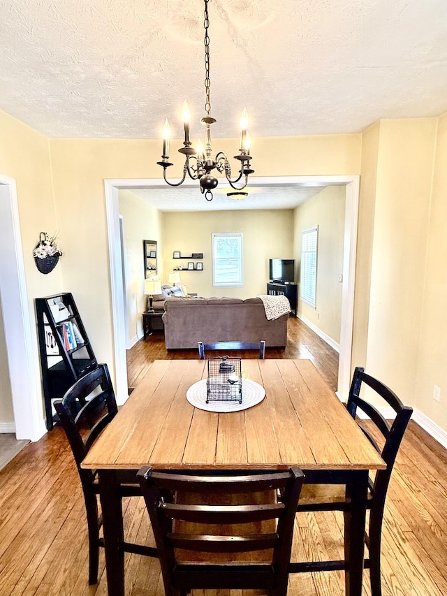 dining room featuring an inviting chandelier, hardwood / wood-style flooring, and a textured ceiling