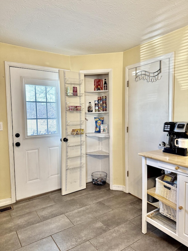 428 Columbia Ave, Monticello, KY 42633 - doorway to outside featuring tile patterned flooring, a textured ceiling, visible vents, and baseboards
