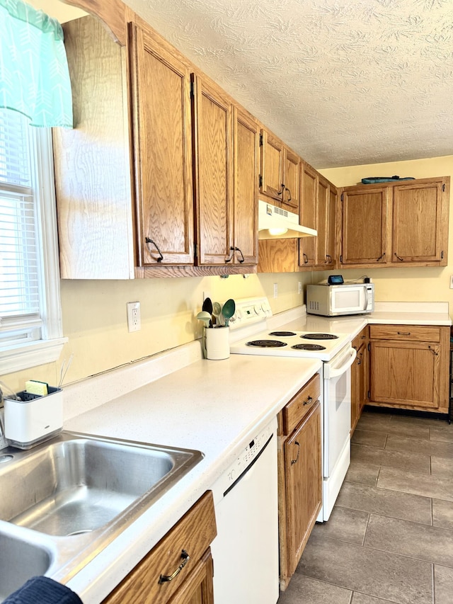 kitchen with sink, a textured ceiling, and white appliances