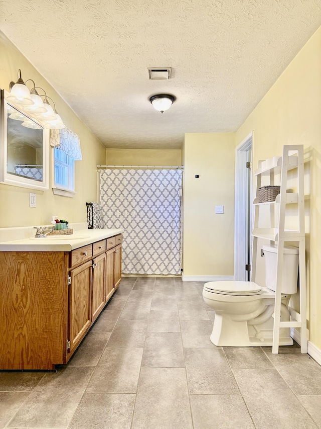 bathroom featuring tile patterned floors, vanity, toilet, and a textured ceiling