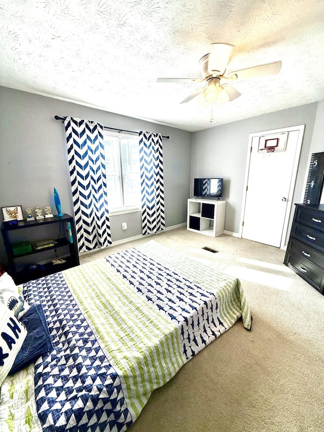 carpeted bedroom with ceiling fan and a textured ceiling