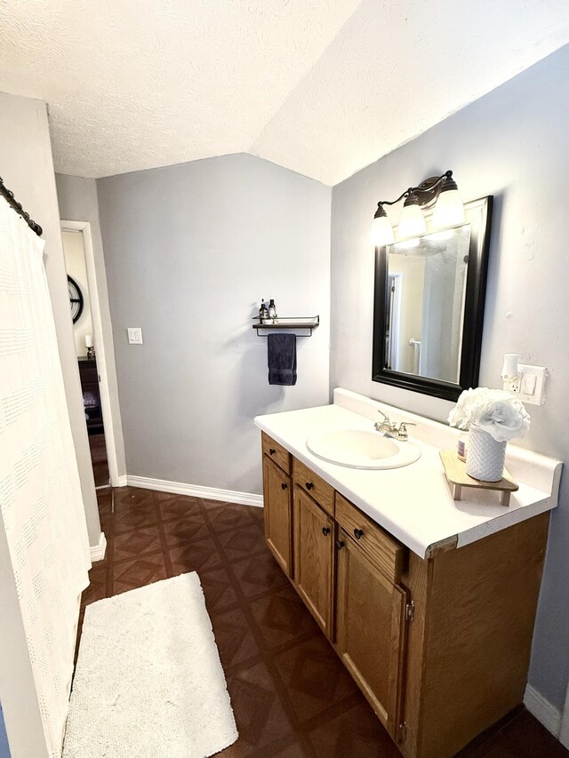 428 Columbia Ave, Monticello, KY 42633 - bathroom with a textured ceiling, vanity, vaulted ceiling, and baseboards