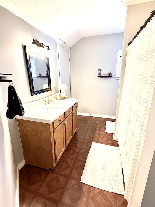 bathroom featuring lofted ceiling, vanity, and parquet floors