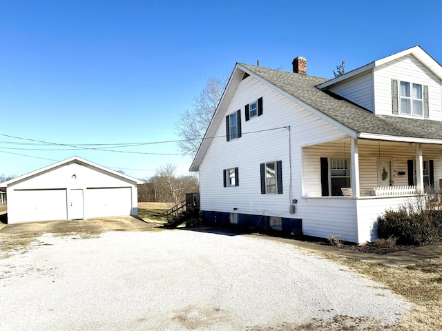 view of side of property with a garage, an outdoor structure, and a porch