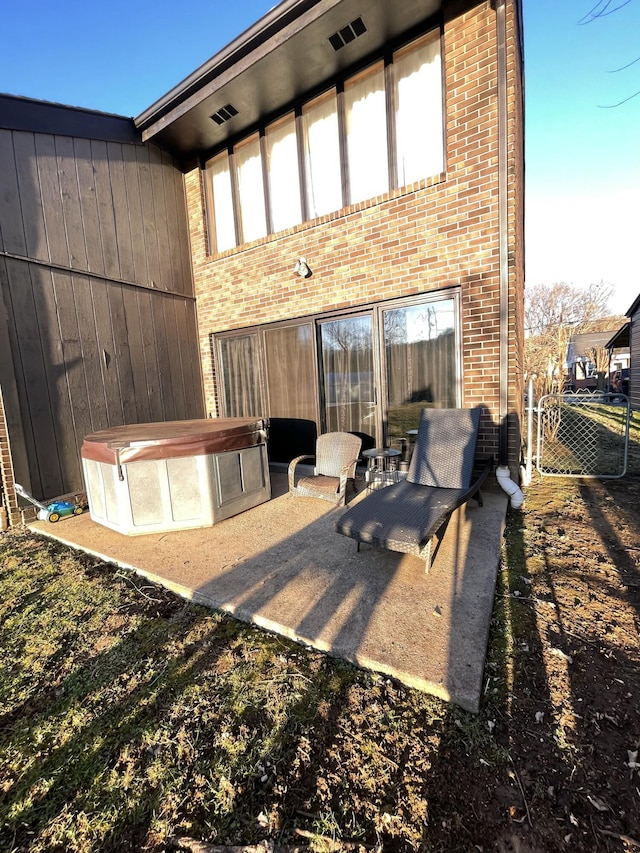 rear view of property featuring a patio area and a jacuzzi