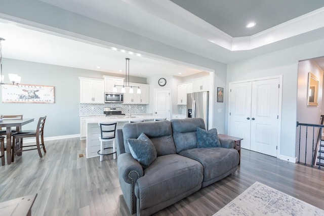 living area with a notable chandelier, recessed lighting, light wood-type flooring, and baseboards