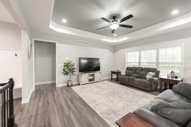 living area with recessed lighting, a raised ceiling, visible vents, and wood finished floors