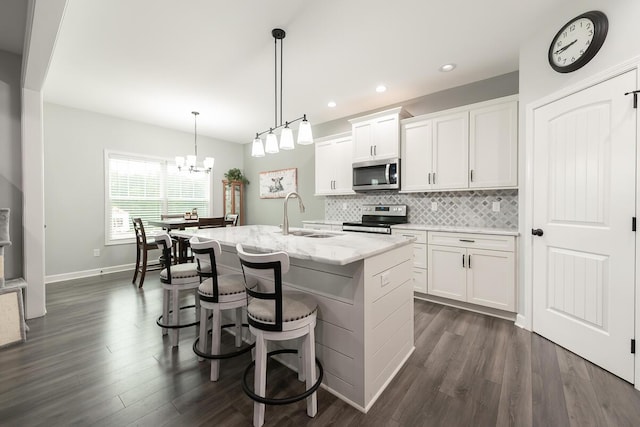 kitchen featuring stainless steel appliances, a sink, white cabinetry, dark wood-style floors, and tasteful backsplash