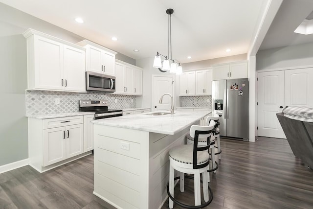 kitchen with white cabinetry, a kitchen bar, appliances with stainless steel finishes, and a sink