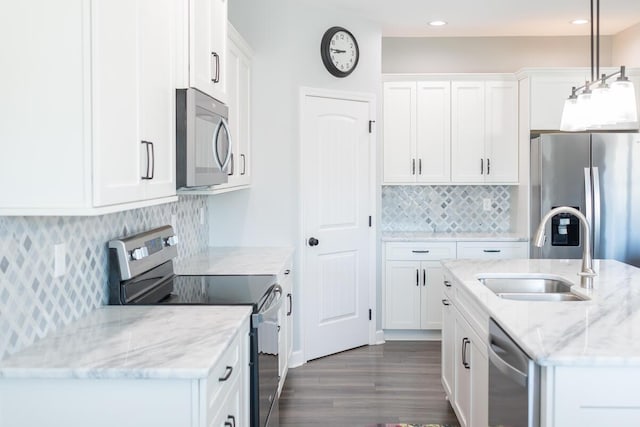 kitchen featuring light stone counters, hanging light fixtures, appliances with stainless steel finishes, white cabinets, and a sink