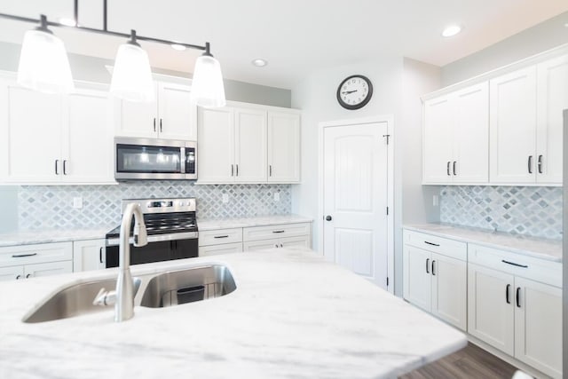 kitchen with stainless steel appliances, white cabinets, a sink, and hanging light fixtures