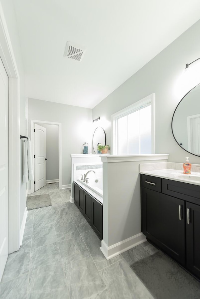 full bath featuring visible vents, a garden tub, vanity, and baseboards