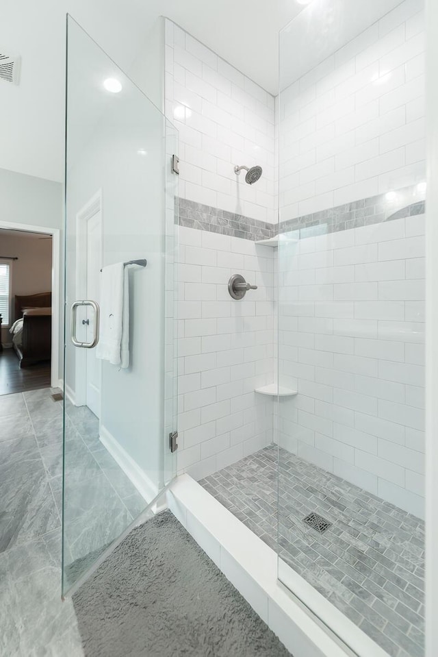 ensuite bathroom featuring visible vents, connected bathroom, a shower stall, and baseboards