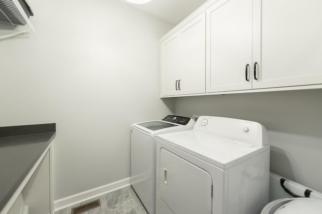 clothes washing area with washer and dryer, cabinet space, visible vents, and baseboards