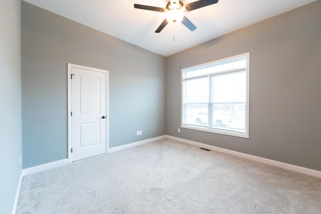 empty room featuring carpet flooring, visible vents, ceiling fan, and baseboards