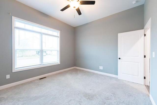 unfurnished room with carpet, visible vents, ceiling fan, and baseboards