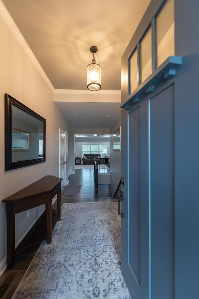 hall featuring baseboards, crown molding, an upstairs landing, and wood finished floors