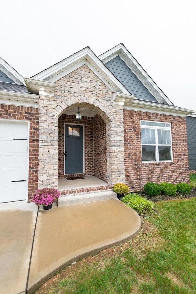 doorway to property with a garage, stone siding, and brick siding