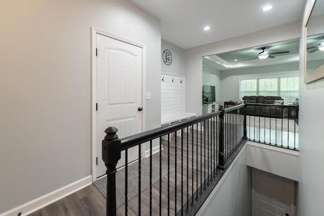 hallway featuring dark wood-type flooring, recessed lighting, an upstairs landing, and baseboards