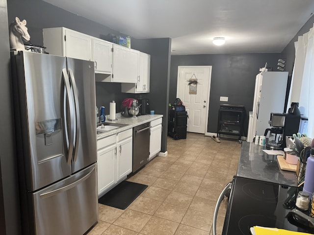 kitchen with light tile patterned floors, stainless steel appliances, sink, and white cabinets