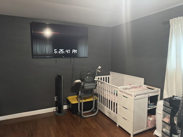 bedroom with a nursery area and dark wood-type flooring