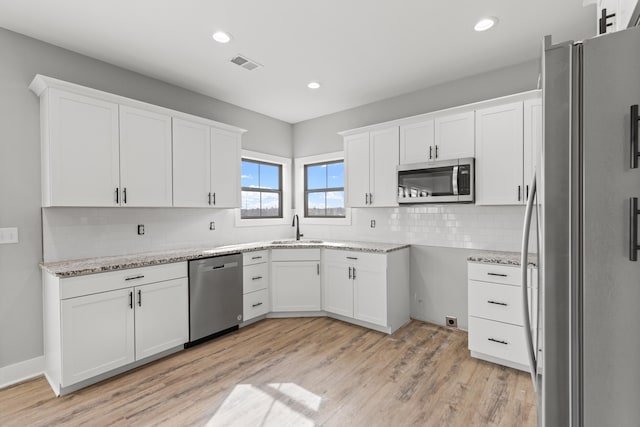 kitchen with white cabinetry, sink, backsplash, and appliances with stainless steel finishes