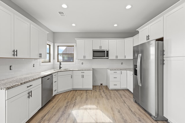 kitchen featuring appliances with stainless steel finishes, sink, white cabinets, and light stone counters