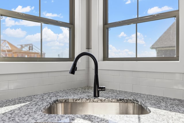 room details featuring light stone countertops, sink, and backsplash