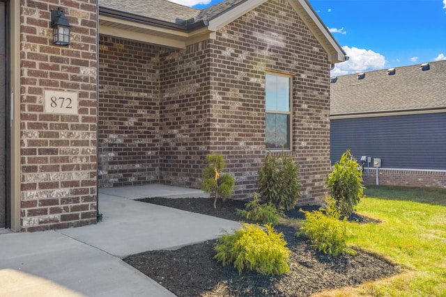 view of exterior entry with a lawn and a patio