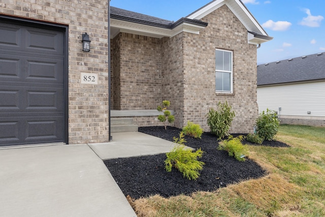 entrance to property with a garage and a lawn