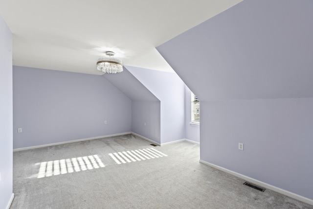 bonus room featuring vaulted ceiling, light colored carpet, and an inviting chandelier