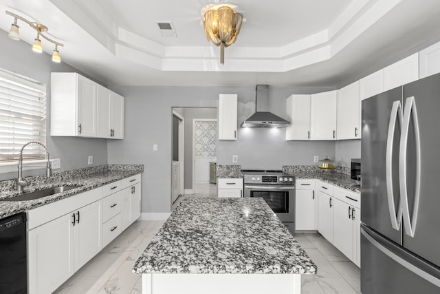 kitchen featuring a kitchen island, white cabinetry, appliances with stainless steel finishes, and wall chimney exhaust hood