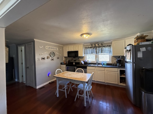 kitchen featuring sink, dark wood-type flooring, stainless steel appliances, ornamental molding, and a textured ceiling