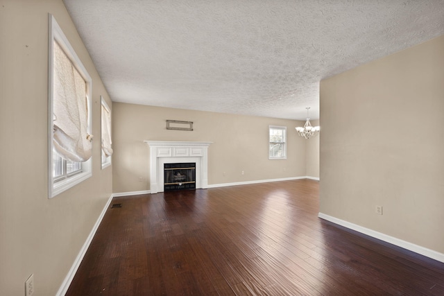 unfurnished living room featuring dark wood-type flooring, a notable chandelier, and a textured ceiling