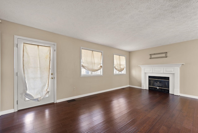 unfurnished living room featuring dark wood-type flooring and a textured ceiling