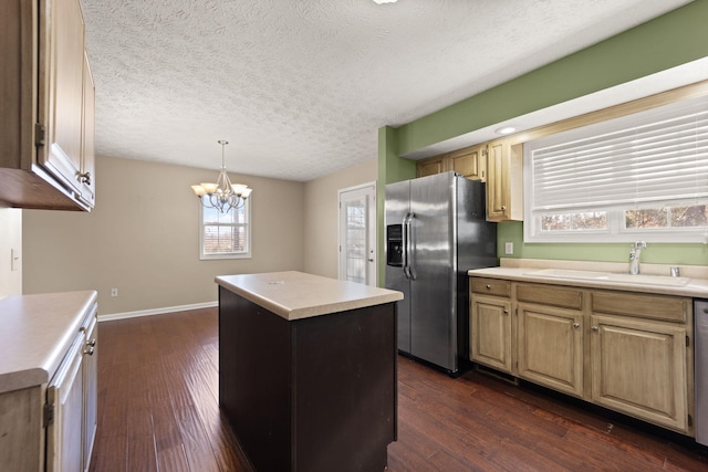 kitchen featuring decorative light fixtures, sink, a center island, stainless steel appliances, and dark wood-type flooring