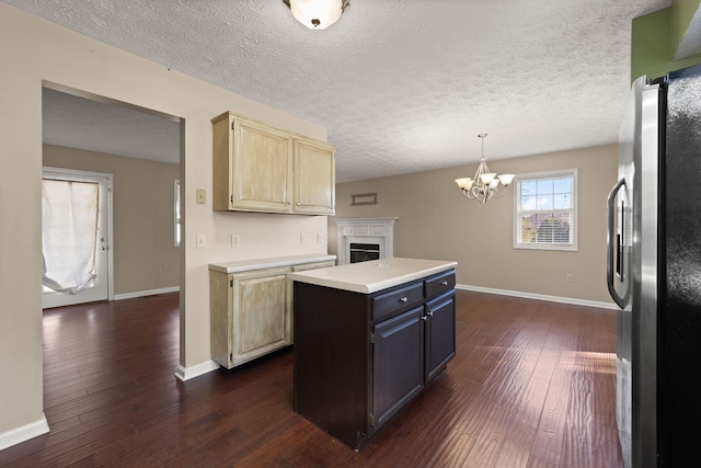 kitchen with decorative light fixtures, stainless steel fridge, dark hardwood / wood-style flooring, a center island, and a notable chandelier